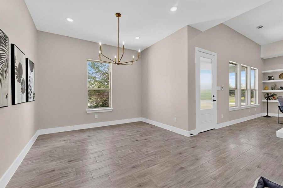 Unfurnished dining area with light wood-style flooring, a chandelier, plenty of natural light, and recessed lighting
