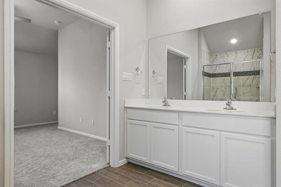 Full bath featuring a marble finish shower, double vanity, and wood finished floors Full bath featuring a marble finish shower, double vanity, and wood finished floors