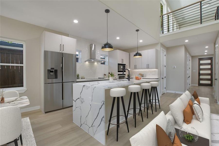 Kitchen featuring white cabinets, island range hood, light hardwood / wood-style flooring, decorative light fixtures, and stainless steel fridge