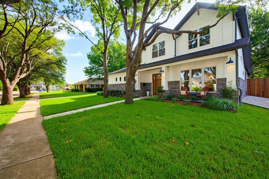 Modern farmhouse-style exterior featuring white vertical siding, dark gray shingle roofing, and stone veneer accents