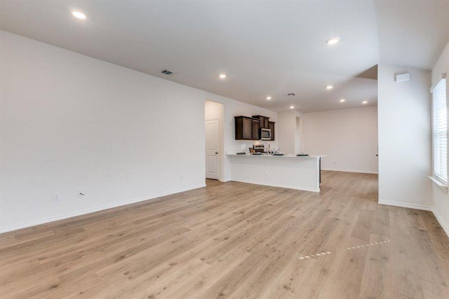 Unfurnished living room with light wood-type flooring and recessed lighting Unfurnished living room with light wood-type flooring and recessed lighting