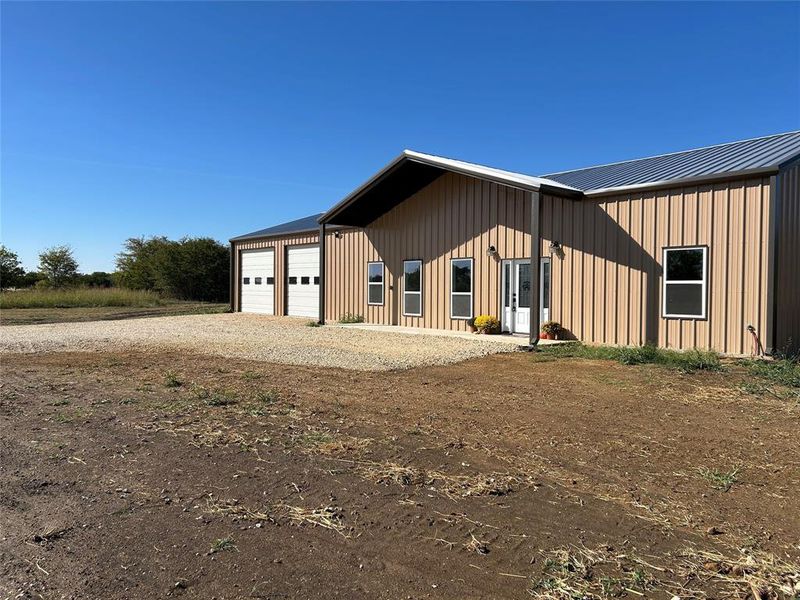 View of front facade with a garage, board and batten siding, driveway, and a metal roof