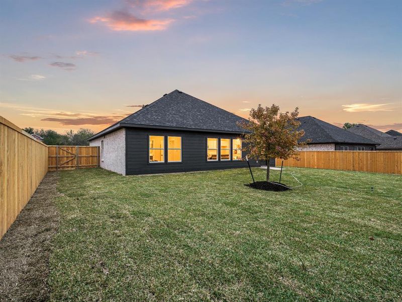 Back house at dusk featuring a yard