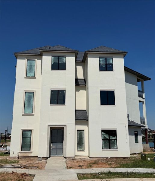 The grand exterior of 4610 Sunset Circle. Sophisticated modern with clean lines of Stucco and Cast Stone, tall windows, and timeless curb appeal. This three-story design offers a striking presence with a welcoming entry and abundant natural light.