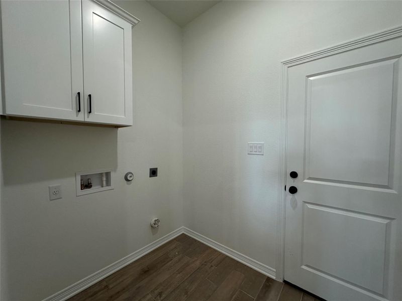 Laundry room with dark wood-type flooring, hookup for a gas dryer, electric dryer hookup, cabinet space, and washer hookup
