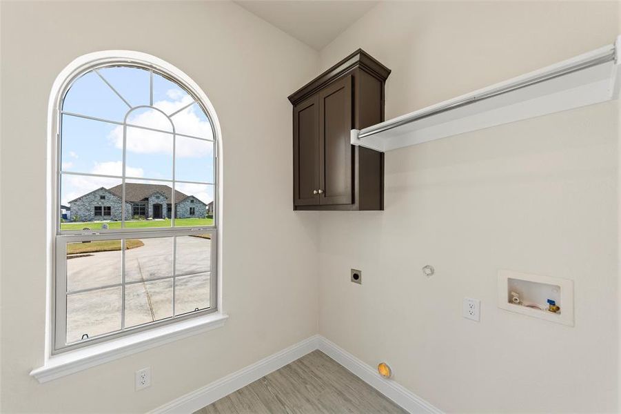 Laundry room with electric dryer hookup, plenty of natural light, gas dryer hookup, and light hardwood / wood-style floors