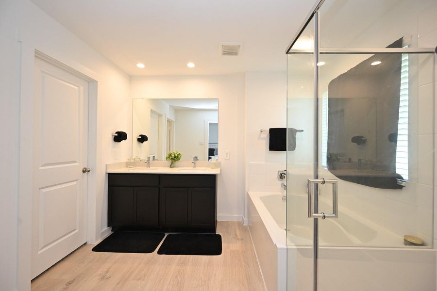 The ensuite bathroom features a modern design with a spacious glass-enclosed shower, a sleek double vanity with dark cabinetry, and light wood flooring. Recessed lighting and a large mirror enhance the bright, airy feel. The ensuite bathroom features a modern design with a spacious glass-enclosed shower, a sleek double vanity with dark cabinetry, and light wood flooring. Recessed lighting and a large mirror enhance the bright, airy feel.