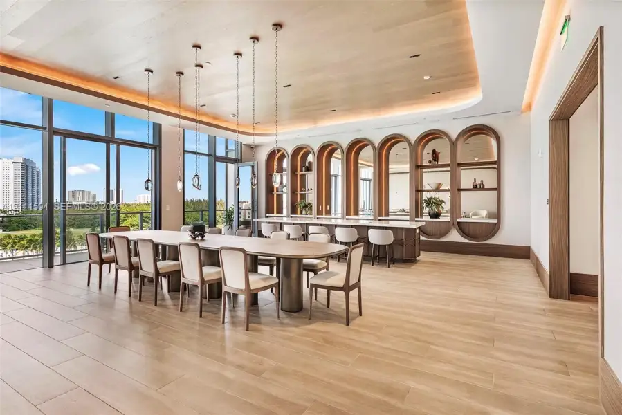 Wood-finish flooring, coved ceiling with recessed lighting, floor-to-ceiling glass paneling, and custom built-in arched cabinetry featuring stone countertops Wood-finish flooring, coved ceiling with recessed lighting, floor-to-ceiling glass paneling, and custom built-in arched cabinetry featuring stone countertops