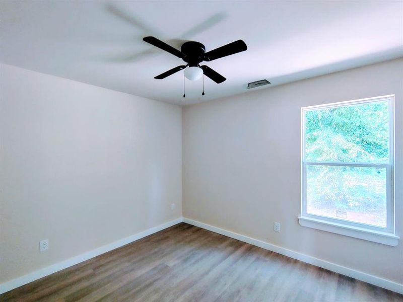 Unfurnished room with plenty of natural light, wood finished floors, and a ceiling fan