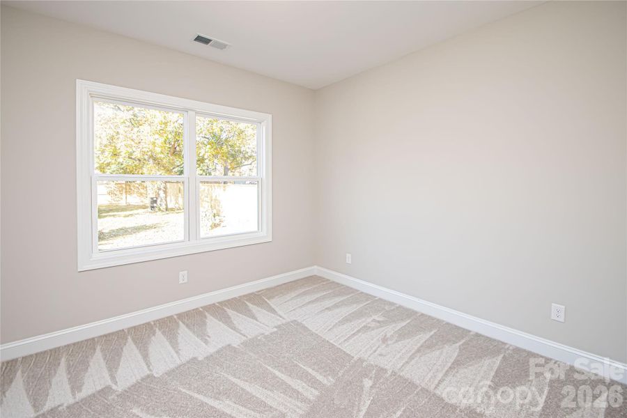 This second bedroom boasts plush carpeting, a roomy closet, a large window for natural light, and a pre-installed outlet for a ceiling fan.