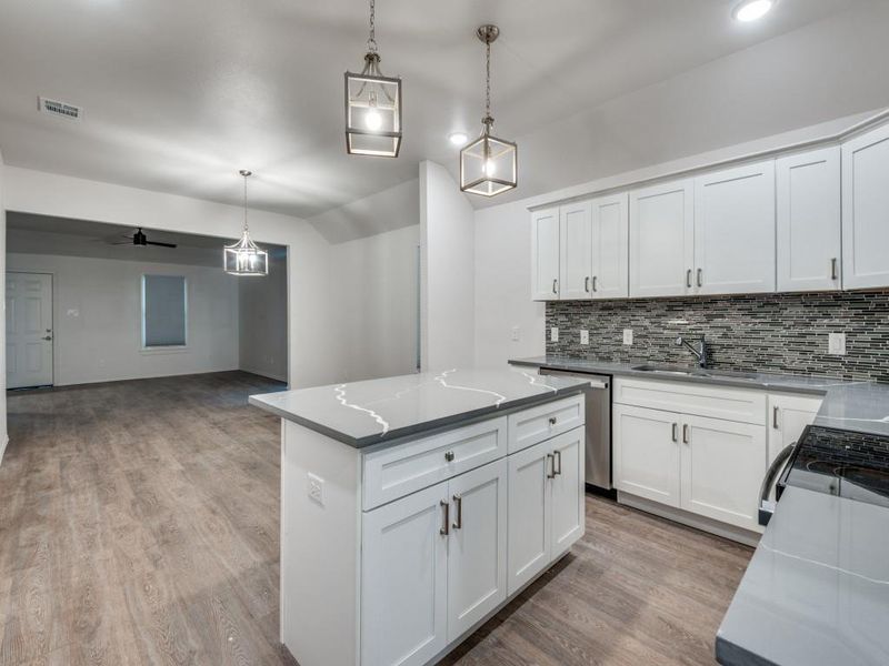 Kitchen featuring light hardwood / wood-style flooring, light stone counters, decorative backsplash, a kitchen island, and dishwasher