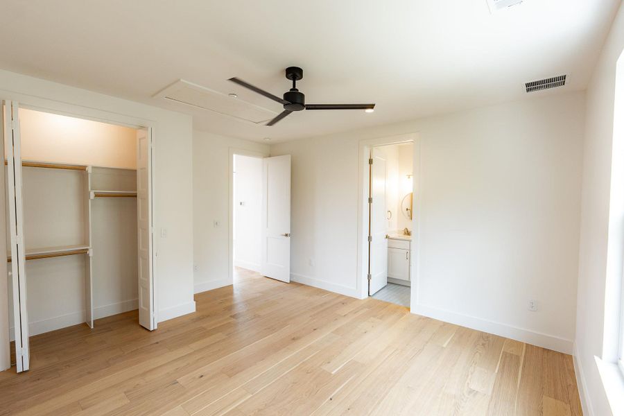 Blonde hardwood floors flow through this light-filled bedroom, complete with a ceiling fan and an adjacent private bath. Blonde hardwood floors flow through this light-filled bedroom, complete with a ceiling fan and an adjacent private bath.