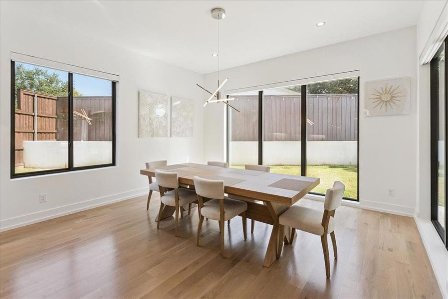 Dining room featuring plenty of natural light, light wood finished floors, a chandelier, and recessed lighting