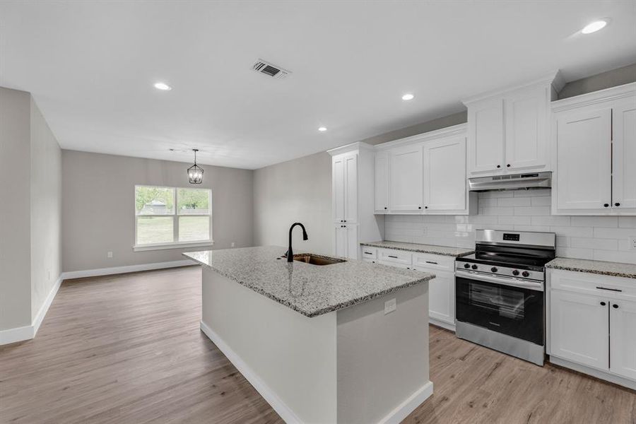 Kitchen featuring white cabinets, light hardwood / wood-style floors, sink, and stainless steel gas range oven