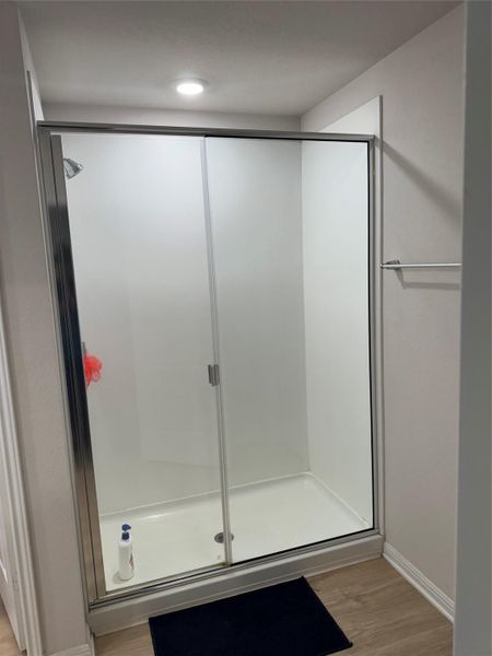 Full bathroom featuring a shower stall and light wood-style flooring