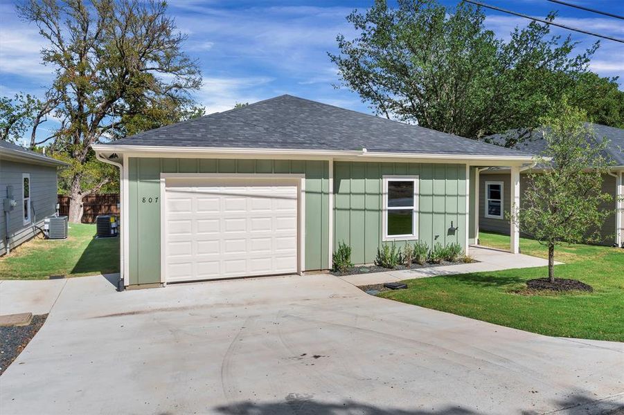 View of front facade with roof with shingles, driveway, board and batten siding, and a front yard View of front facade with roof with shingles, driveway, board and batten siding, and a front yard