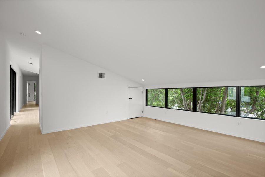 Unfurnished room with recessed lighting, light wood-style flooring, and vaulted ceiling