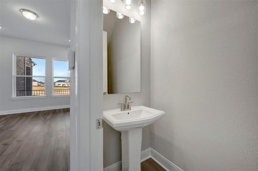 Half bathroom with dark wood-type flooring and baseboards