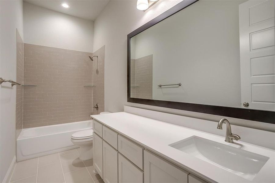 Full bathroom featuring tiled shower / bath combo, tile patterned floors, toilet, and vanity