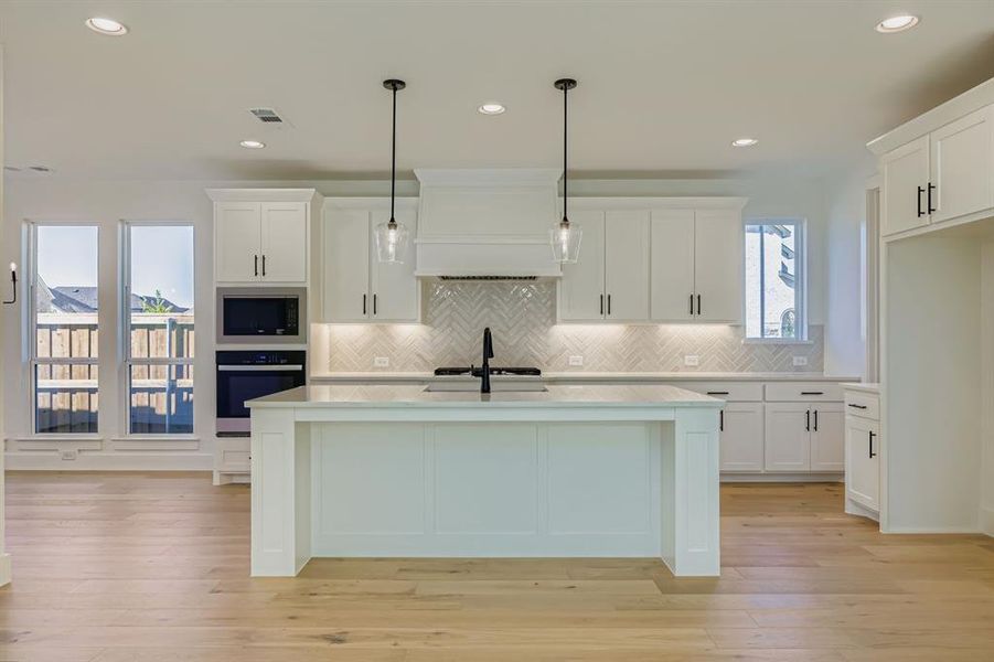 Kitchen featuring a kitchen island with sink, white cabinetry, hanging light fixtures, decorative backsplash, and recessed lighting Kitchen featuring a kitchen island with sink, white cabinetry, hanging light fixtures, decorative backsplash, and recessed lighting