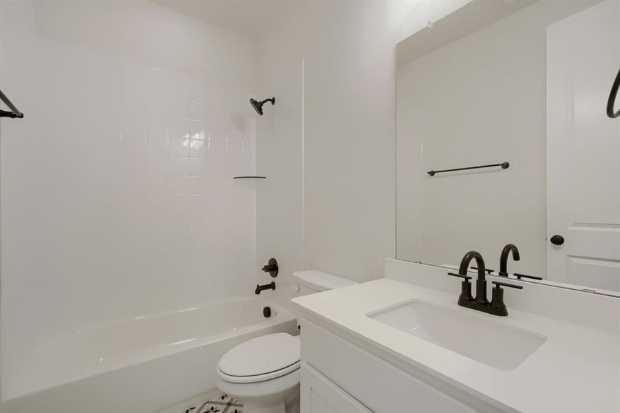 Modern bathroom featuring a white vanity with an integrated sink, a large wall-mounted mirror, and black hardware