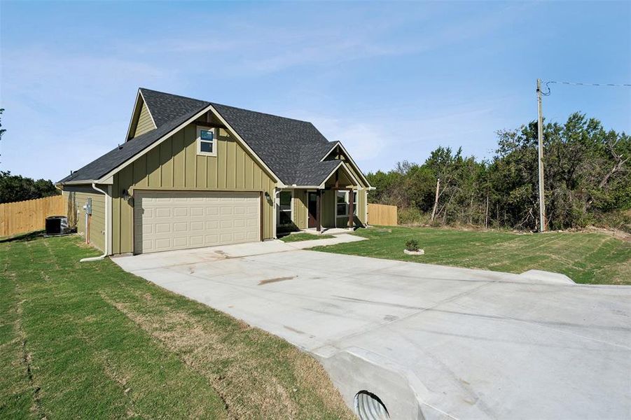 View of front of home featuring a front yard, a garage, and cooling unit