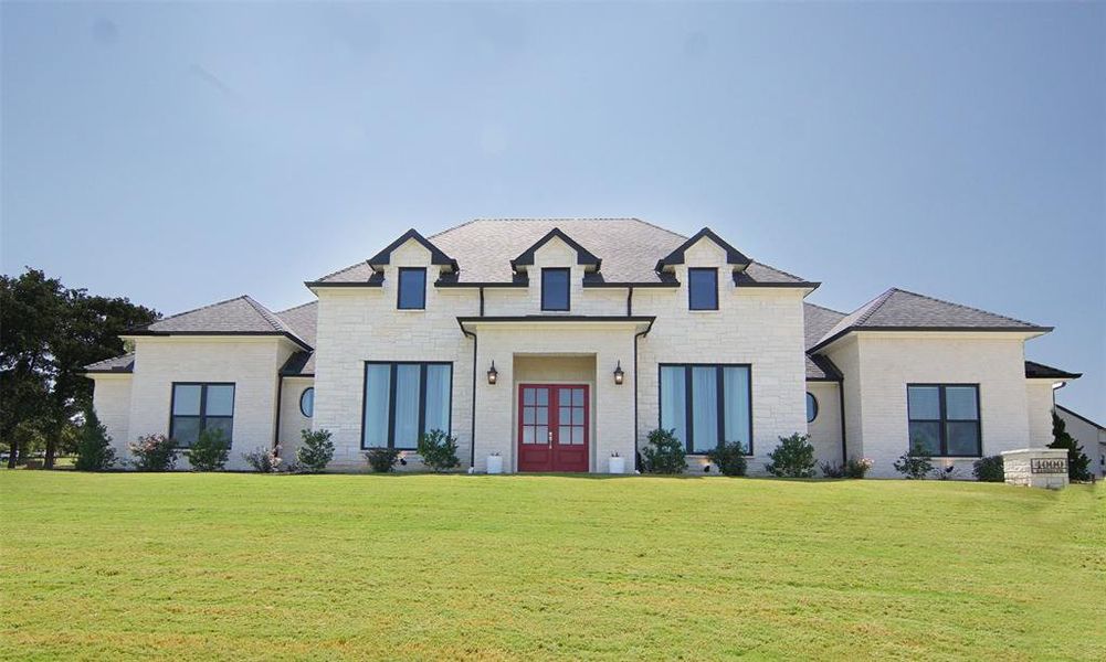 French country inspired facade with a front lawn and french doors