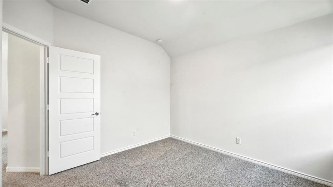 Carpeted spare room featuring lofted ceiling and baseboards