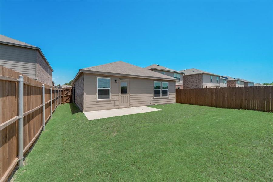 Back of house featuring a patio, nice lawn and wood fence.