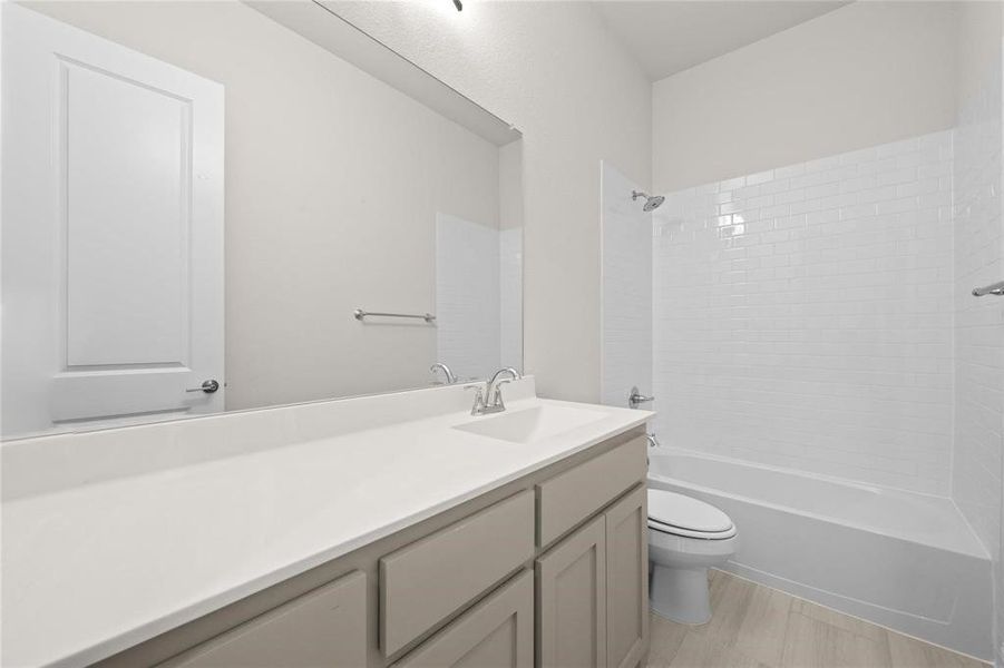 Full bathroom with tiled shower / bath combo, vanity, toilet, and hardwood / wood-style floors