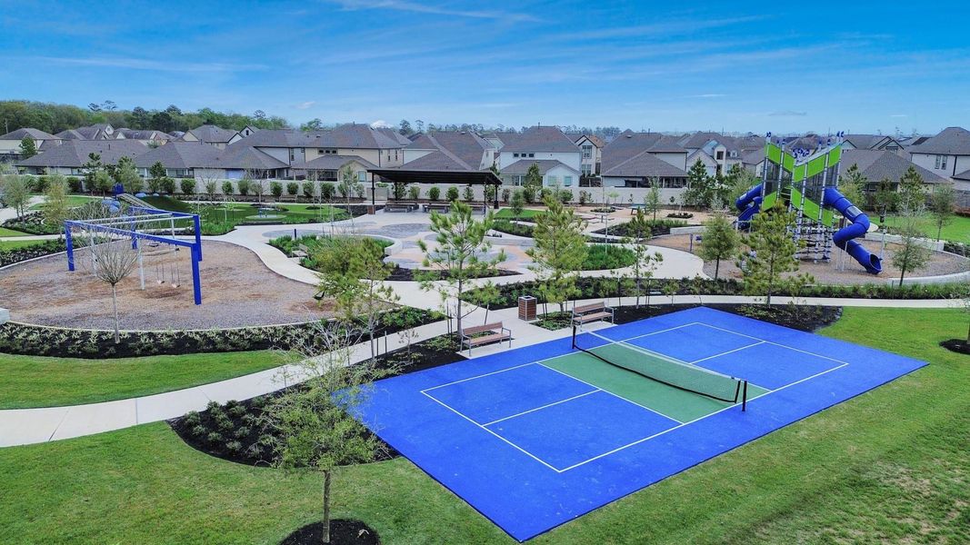 Community recreational courts located within the neighborhood park, offering space for tennis or pickleball alongside playground areas, shaded seating, and walking paths for residents to enjoy.