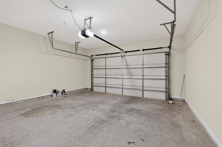 Attached garage featuring a concrete floor, light-toned walls, a sectional garage door, and an overhead garage door opener