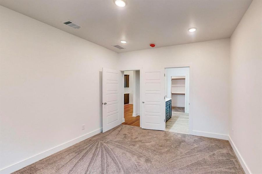 Unfurnished bedroom with a spacious closet, light carpet, and a closet