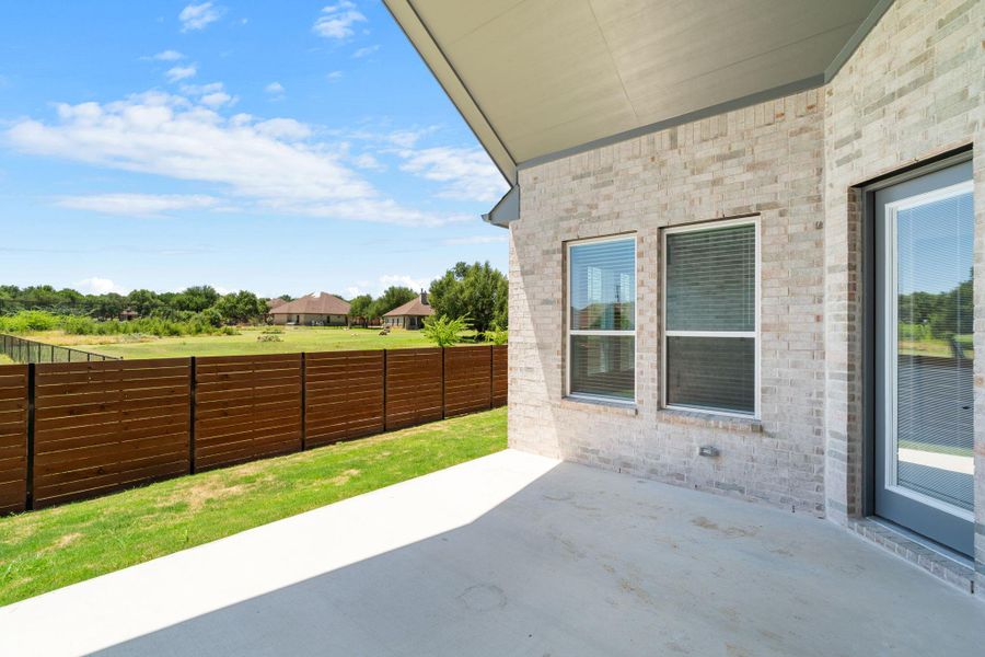 An inviting backyard patio space offers views of the surrounding green landscape and adjacent residences.