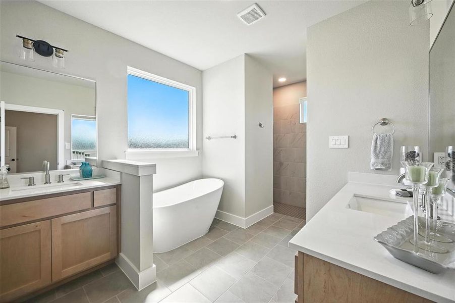 Full bathroom with a freestanding tub, two vanities, a walk in shower, and light tile patterned flooring
