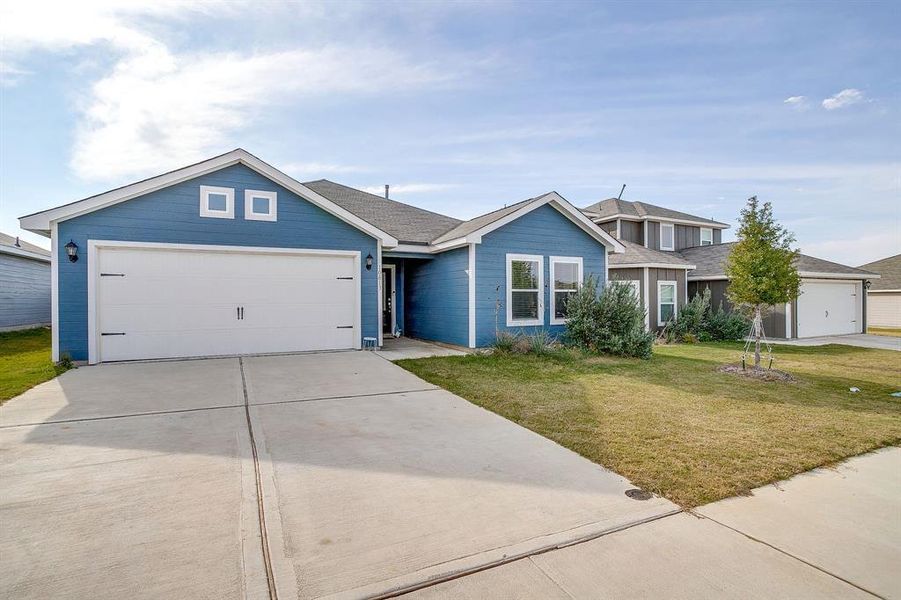 View of front facade with a front lawn, concrete driveway, an attached garage, and roof with shingles
