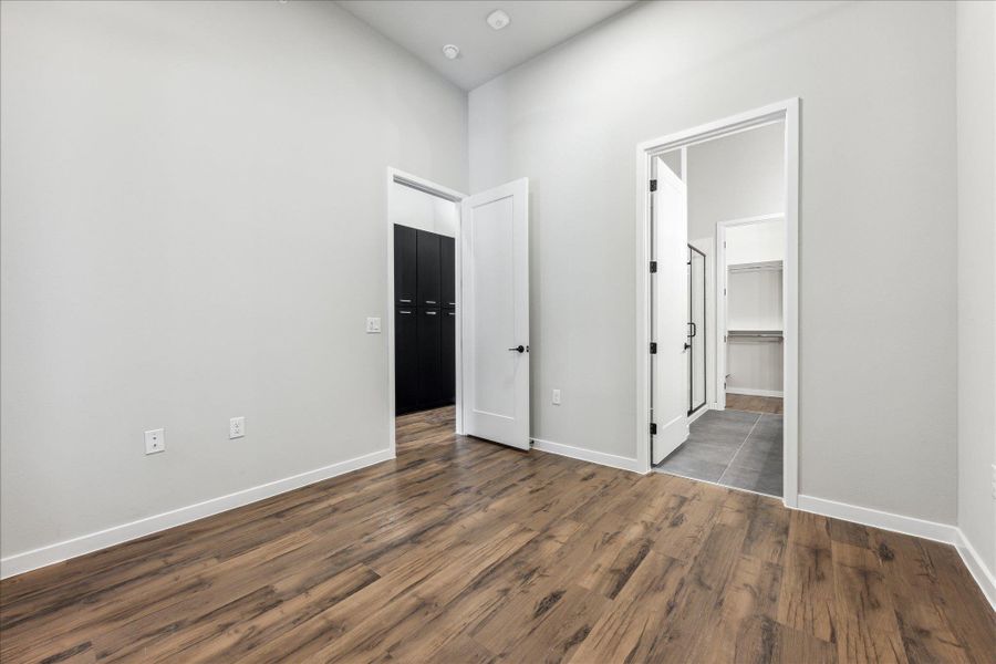 Natural wood-look flooring and tall ceilings elevate this generously sized sleeping space. Natural wood-look flooring and tall ceilings elevate this generously sized sleeping space.