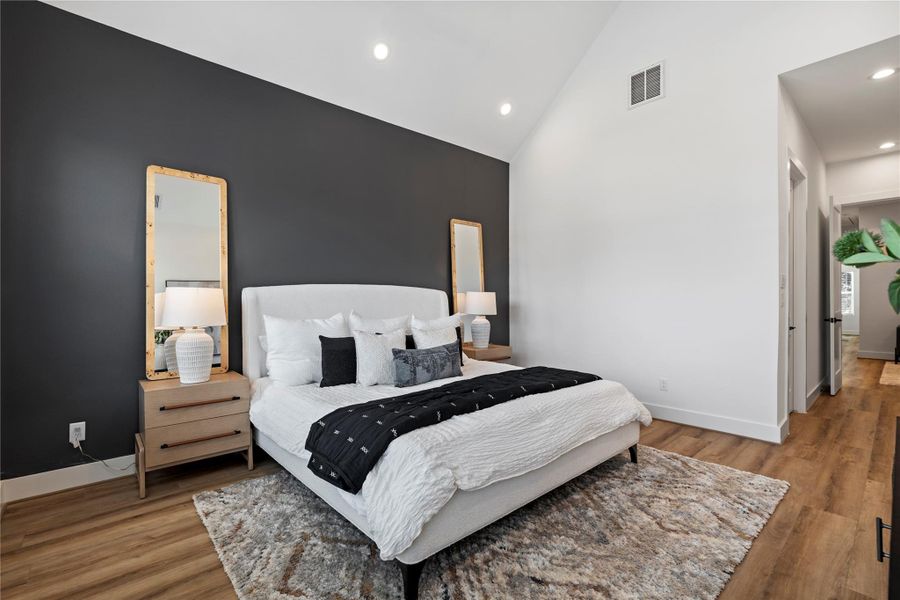 The primary suite makes a bold statement with a custom accent wall, adding warmth and character to the space — a perfect backdrop to unwind beneath vaulted ceilings and sunlit windows.