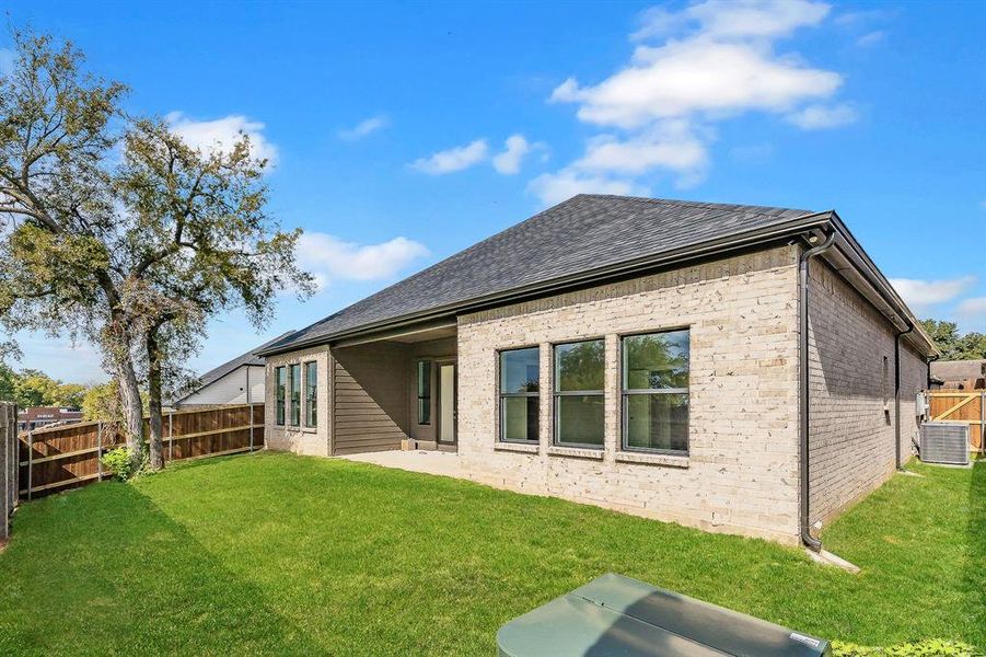 Rear view of house with a patio area, a fenced backyard, brick siding, and a shingled roof