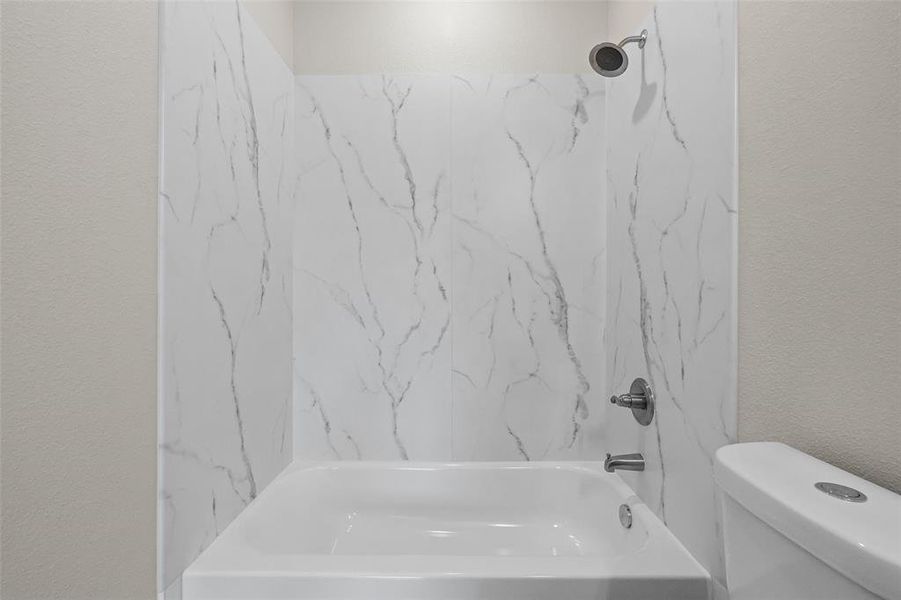 Bathroom featuring tiled shower / bath combo and toilet