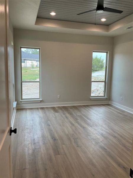 Primary bedroom is 17x14 with tray ceiling, recessed lights, ceiling fan and durable  luxury vinyl wide plank flooring.