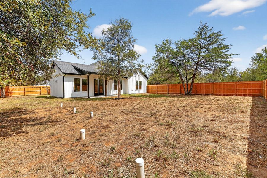 Modern farmhouse with board and batten siding, a fenced backyard, and a patio area