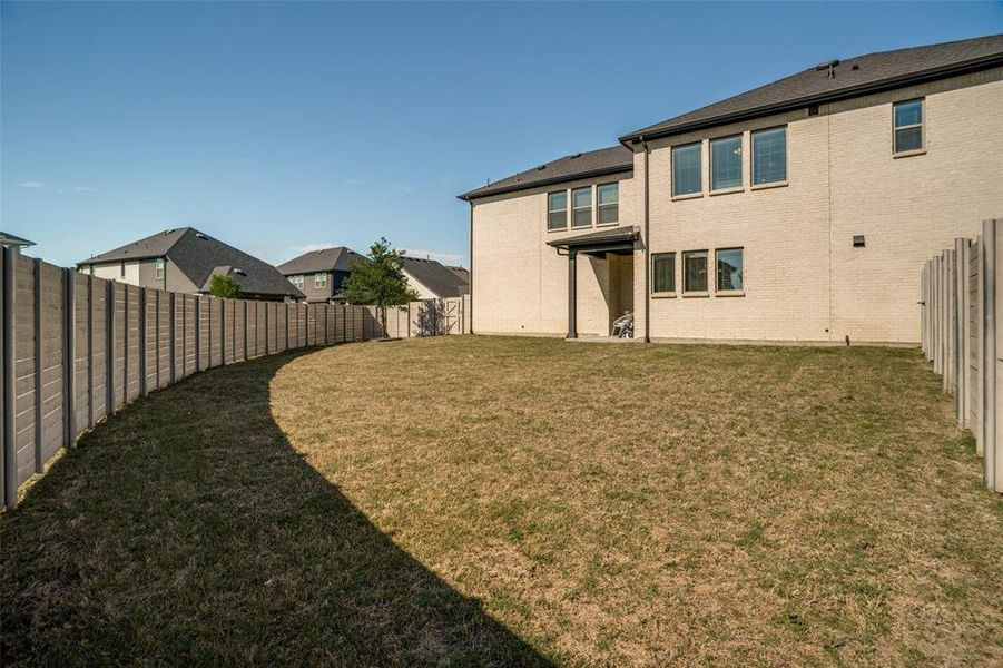 Back of property featuring a fenced backyard and brick siding