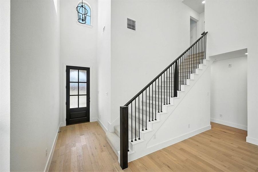 Entrance foyer featuring plenty of natural light, a towering ceiling, stairway, and light wood finished floors Entrance foyer featuring plenty of natural light, a towering ceiling, stairway, and light wood finished floors