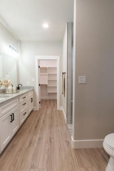 Bathroom with wood finished floors, vanity, toilet, baseboards, and recessed lighting