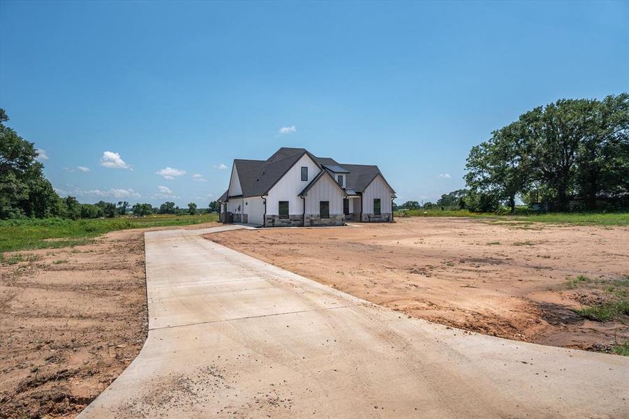 Modern inspired farmhouse with concrete driveway, board and batten siding, and an attached garage