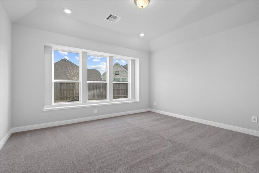 Relax and unwind after a long day in this impressive primary suite! This generously sized room offers plush carpet  flooring, neutral-toned paint, high sloped ceilings, and large windows with seating sill!