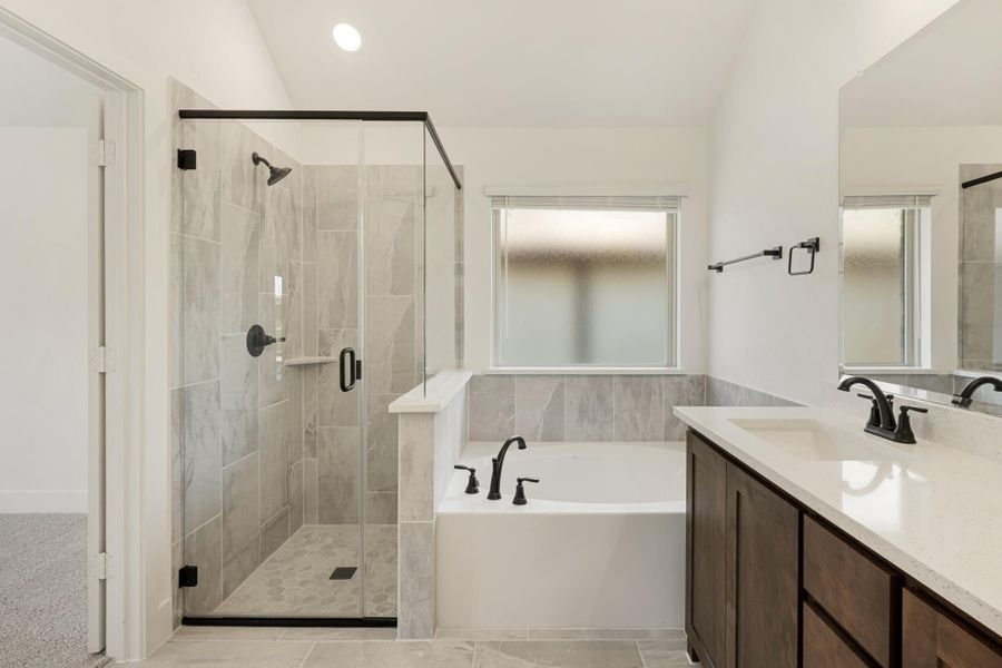 Master bathroom with glass walk-in shower, soaking tub, and dark wood vanity with quartz countertop