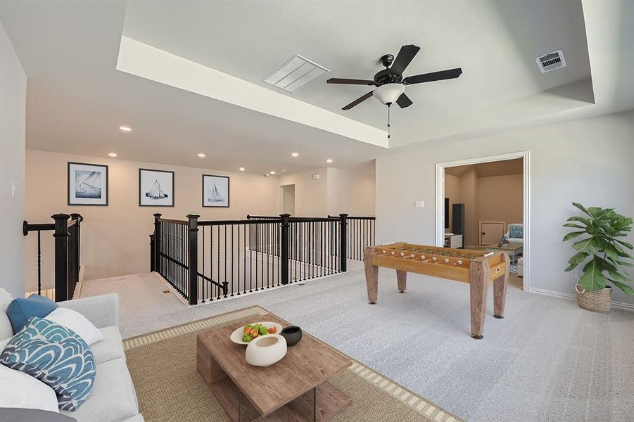 VIRTUALLY STAGED PHOTO -Game room featuring a tray ceiling, light carpet, and ceiling fan