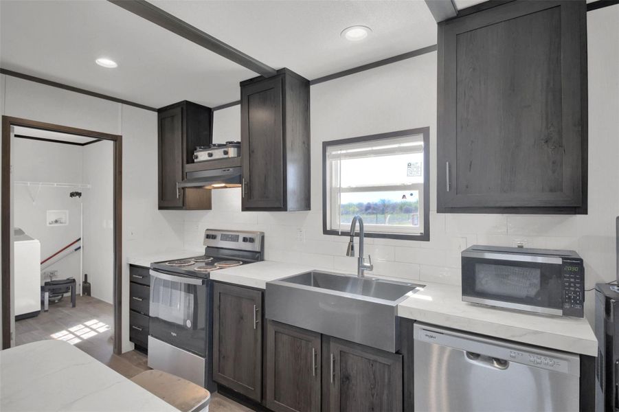 Kitchen with stainless steel appliances, dark wood finish cabinets, washer / clothes dryer, and decorative backsplash